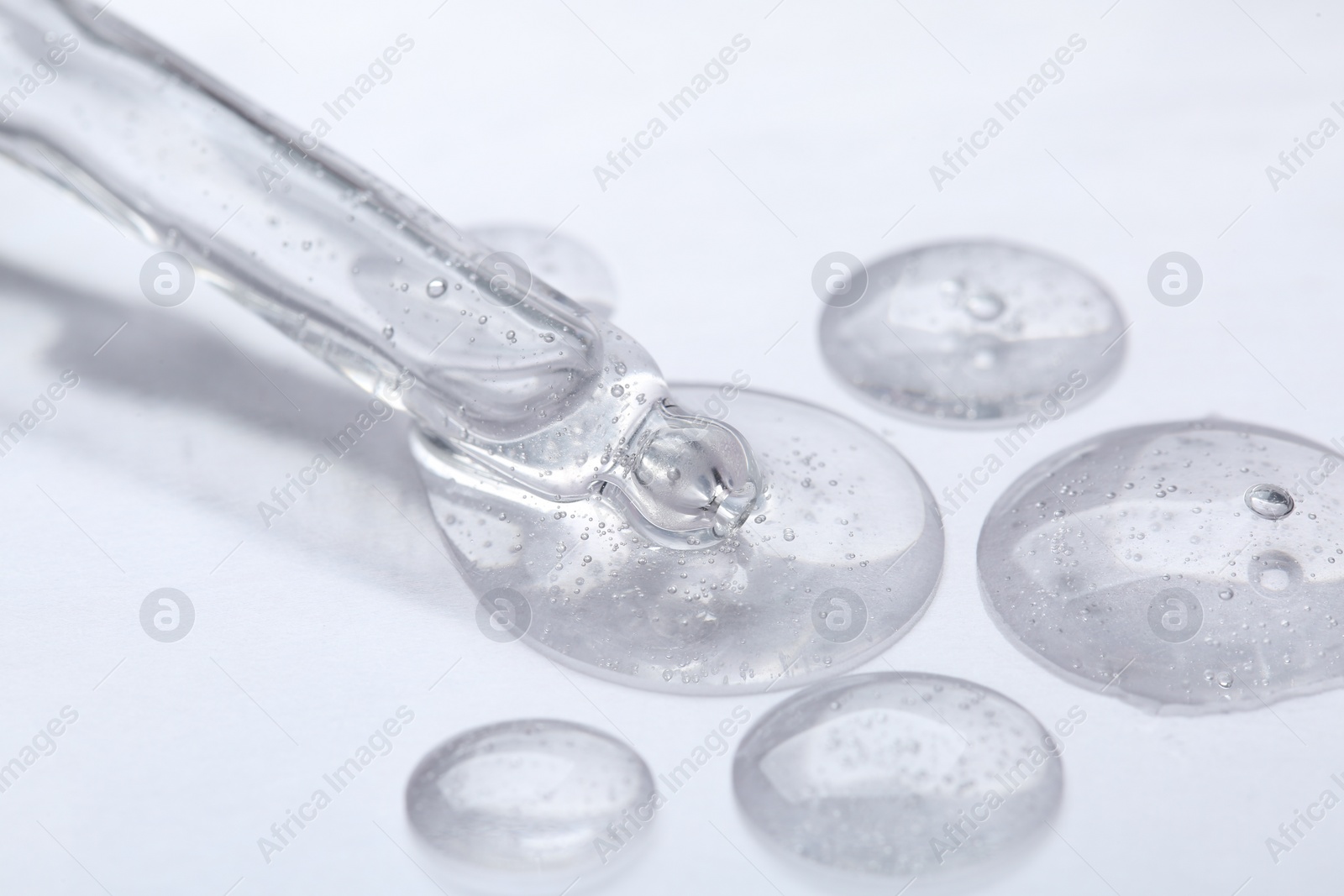 Photo of Pipette with samples of cosmetic serum on white background, closeup