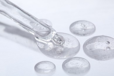 Pipette with samples of cosmetic serum on white background, closeup