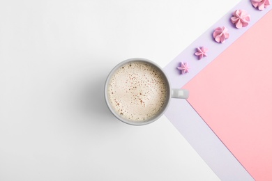 Photo of Cup of coffee and meringues on color background, top view. Space for text