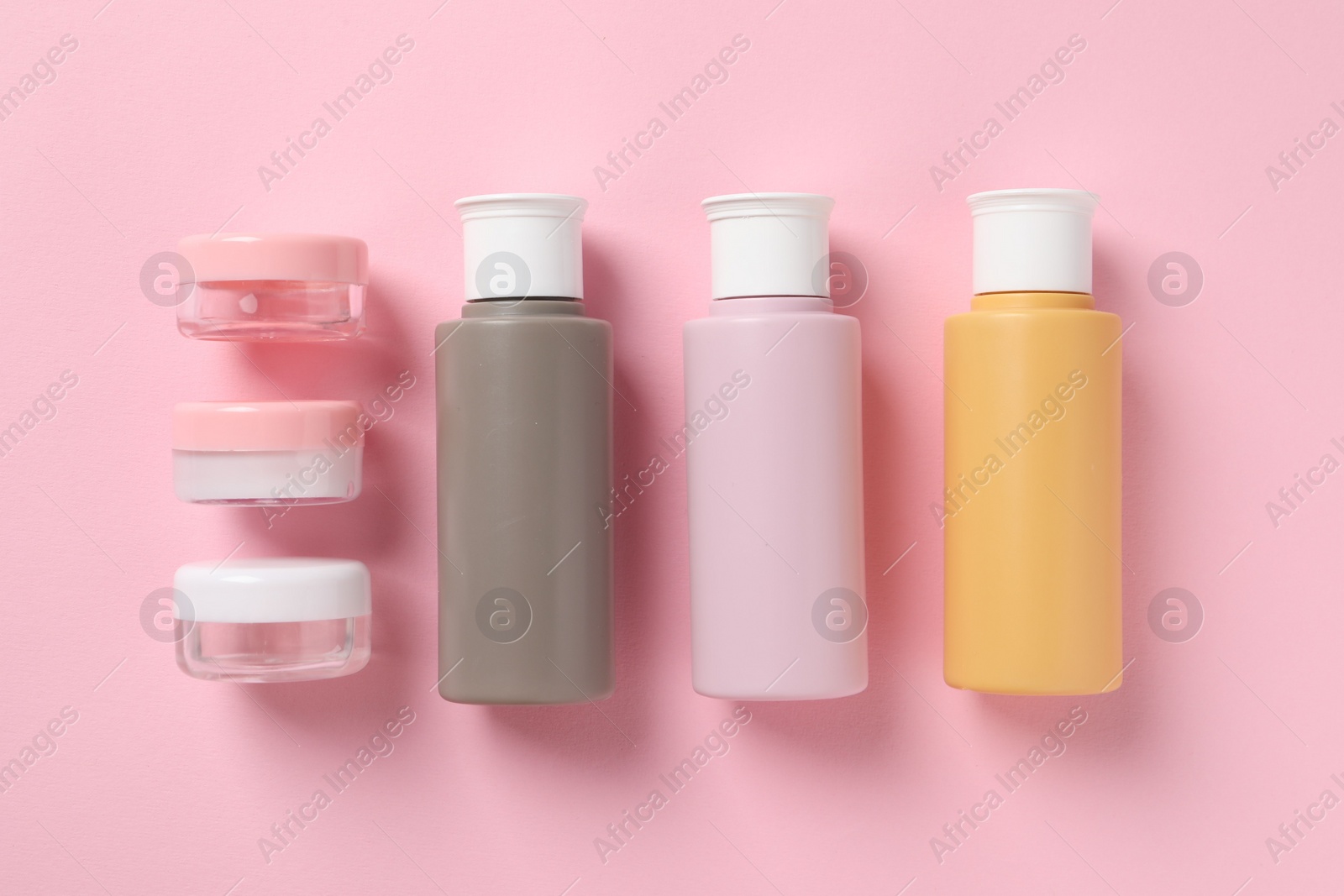 Photo of Cosmetic travel kit on pink background, flat lay. Bath accessories