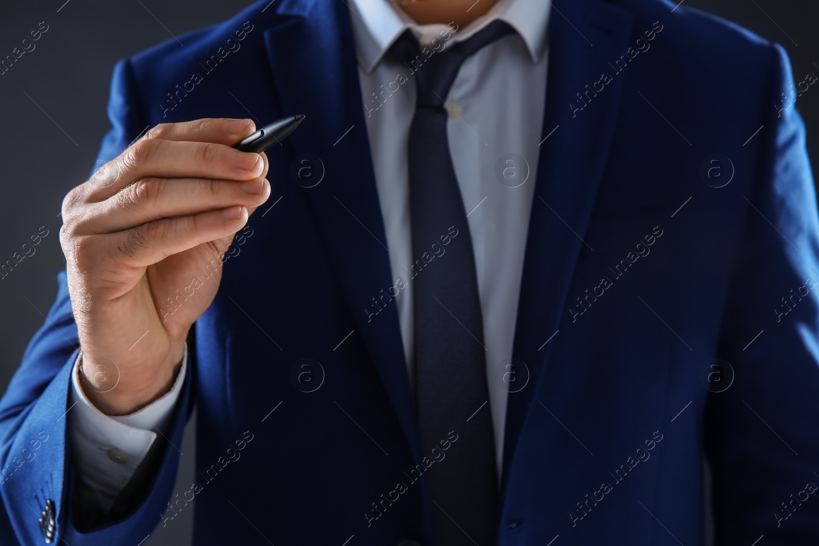 Photo of Businessman holding pen in hand on dark background