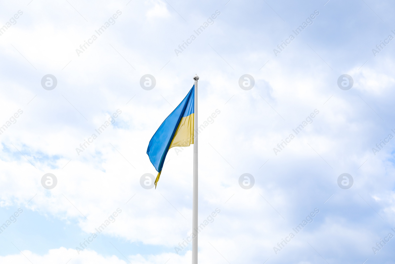 Photo of Flag of Ukraine waving on pole under blue sky