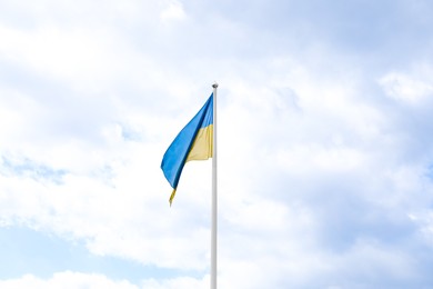 Flag of Ukraine waving on pole under blue sky