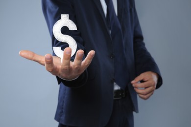 Image of Man demonstrating virtual dollar sign on light grey background, closeup