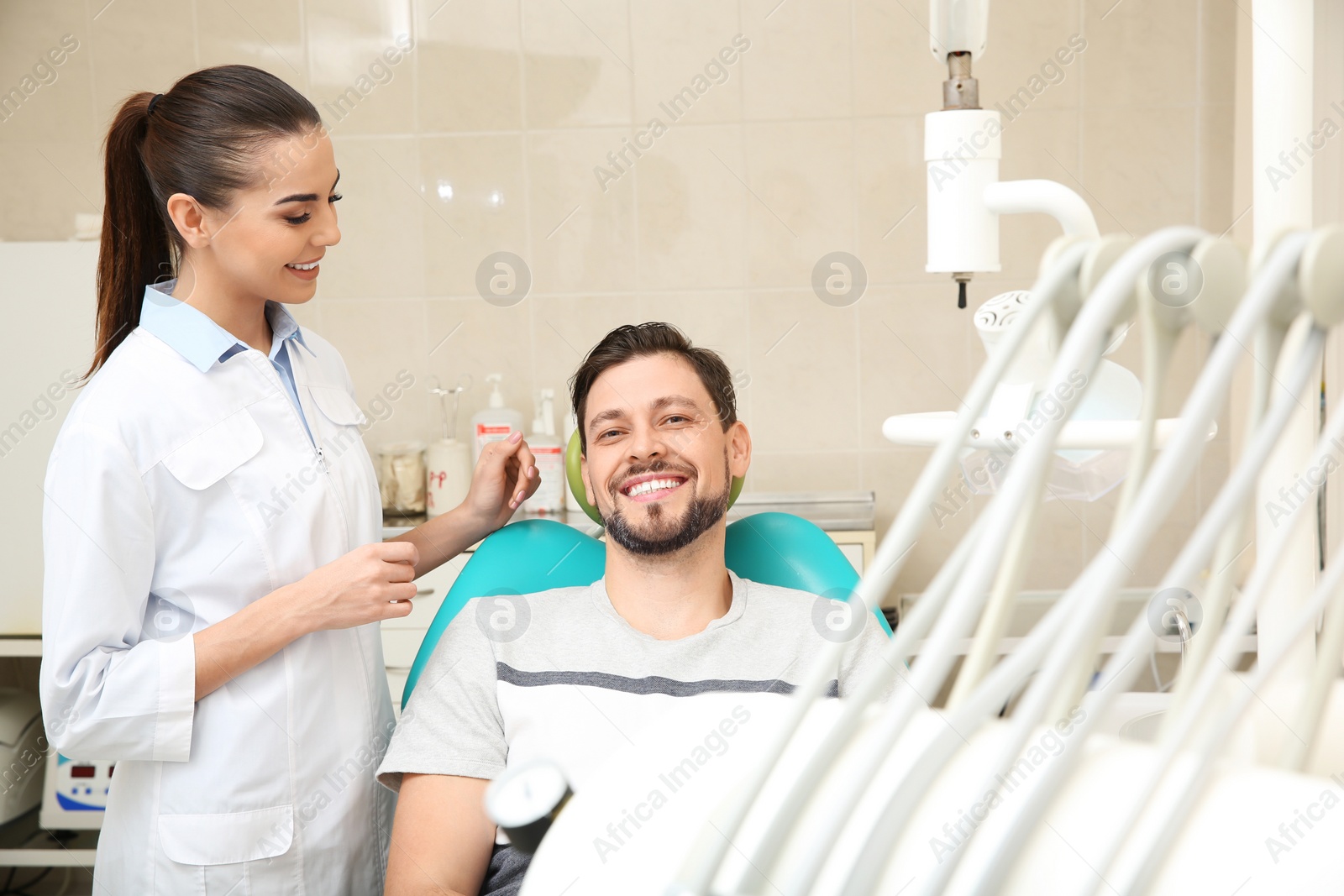 Photo of Professional dentist working with patient in modern clinic