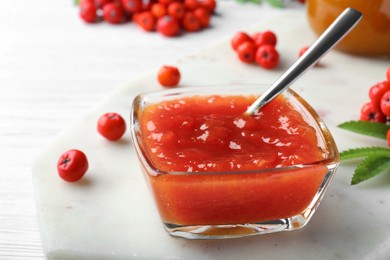 Photo of Delicious rowan jam in glass bowl on white wooden table, closeup