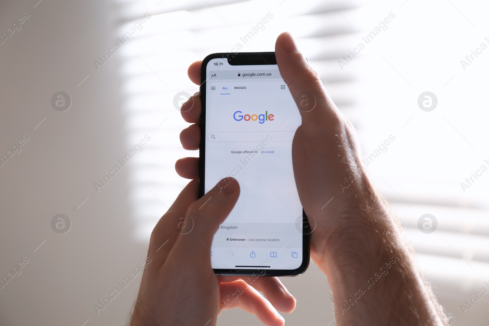 Photo of MYKOLAIV, UKRAINE - OCTOBER 27, 2020: Man using Google search engine on smartphone against blurred background, closeup