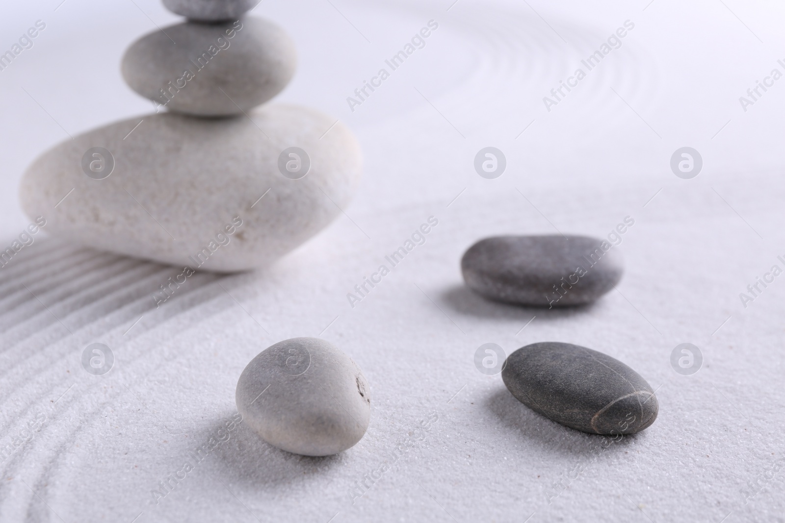 Photo of Zen garden stones on white sand with pattern, closeup