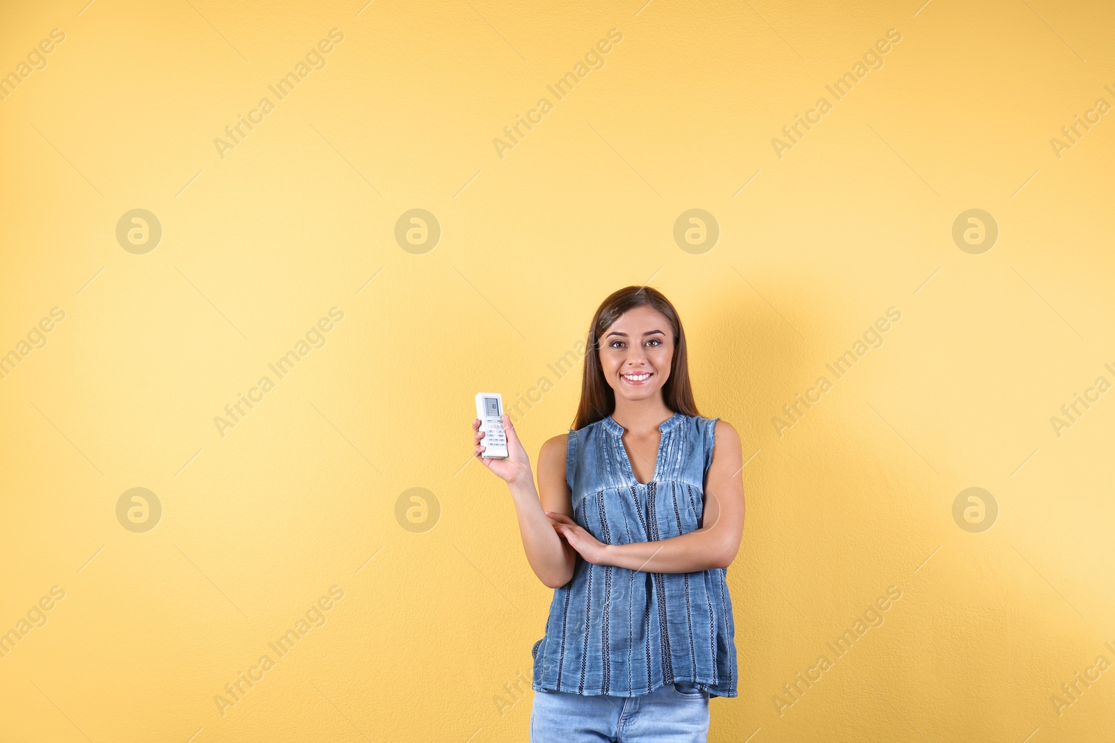 Photo of Young woman with air conditioner remote on color background