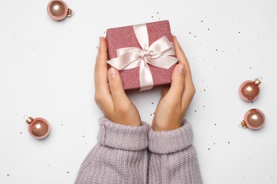 Photo of Young woman holding Christmas gift on white background, flat lay