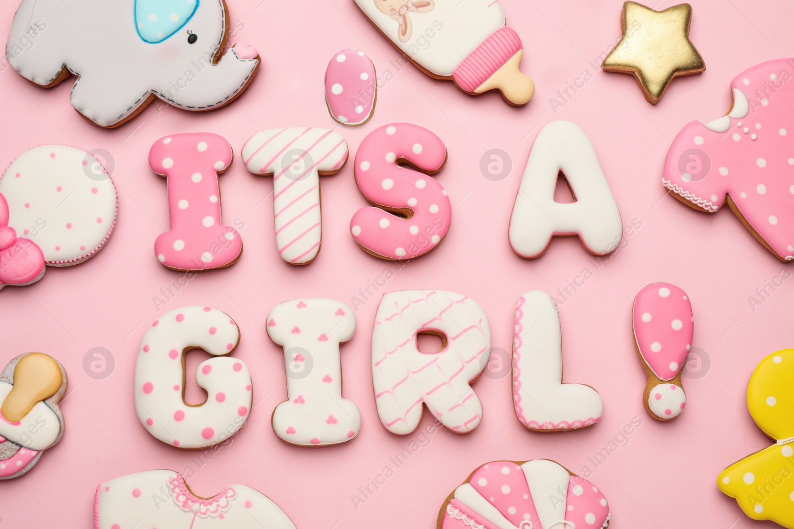Photo of Phrase IT IS A GIRL and tasty cookies on pink background, flat lay. Baby shower party