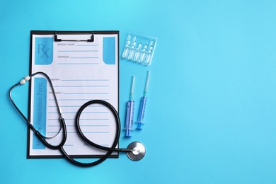 Photo of Clipboard with medical prescription form, stethoscope, ampoules and syringes on light blue background, flat lay. Space for text