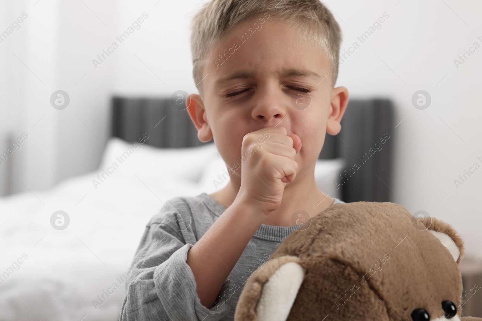 Photo of Sick boy with teddy bear coughing at home