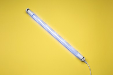 Photo of Ultraviolet lamp on yellow background, top view