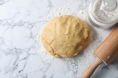 Photo of Making shortcrust pastry. Raw dough, flour and rolling pin on white marble table, flat lay. Space for text