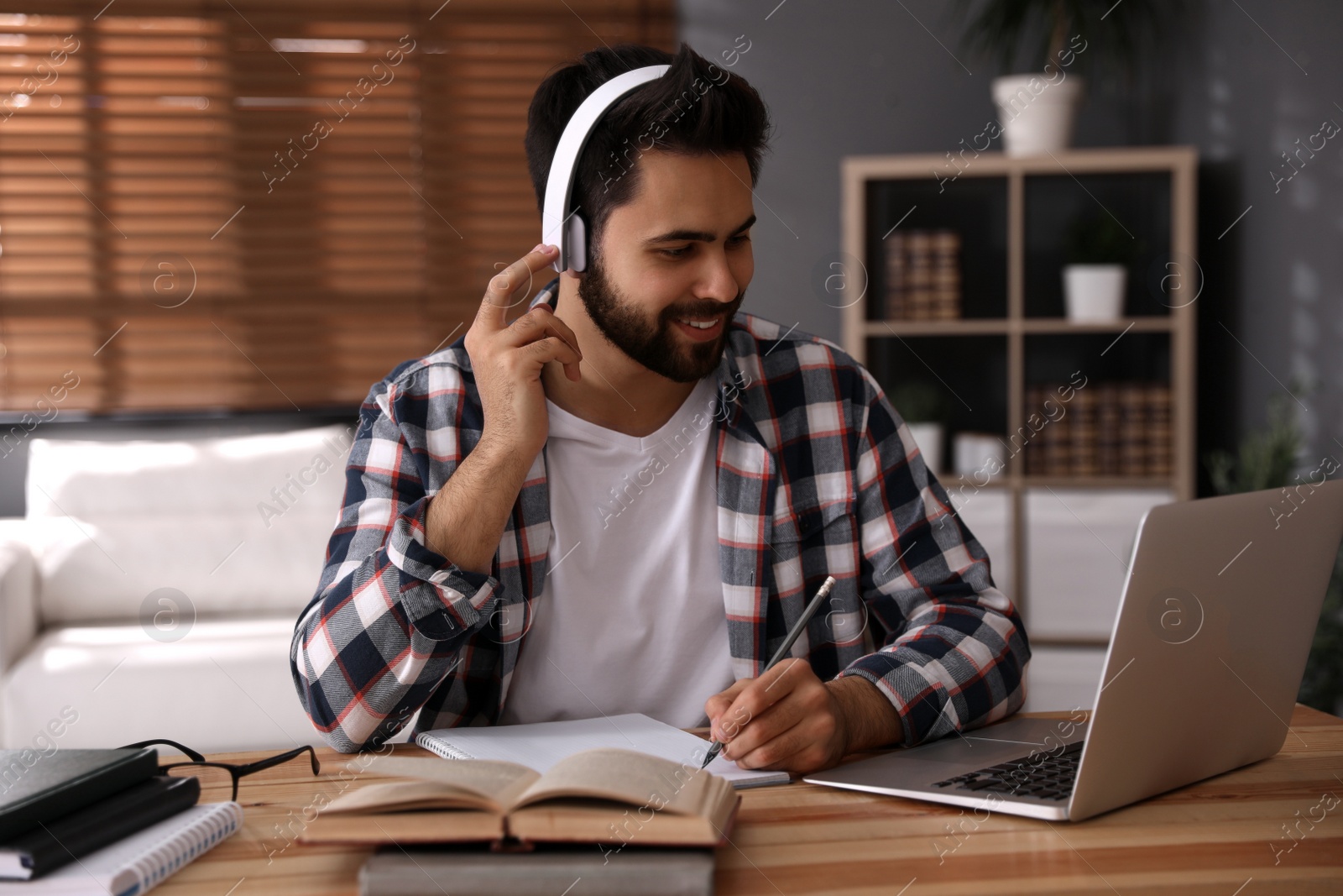 Photo of Young man watching webinar at table in room