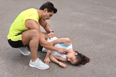 Young man checking pulse of unconscious woman on street