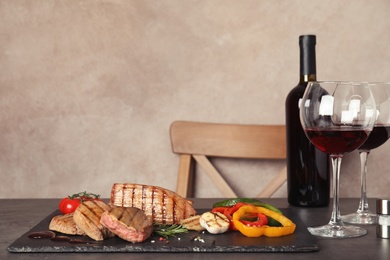 Photo of Grilled meat served with garnish, sauce and wine on table. Space for text