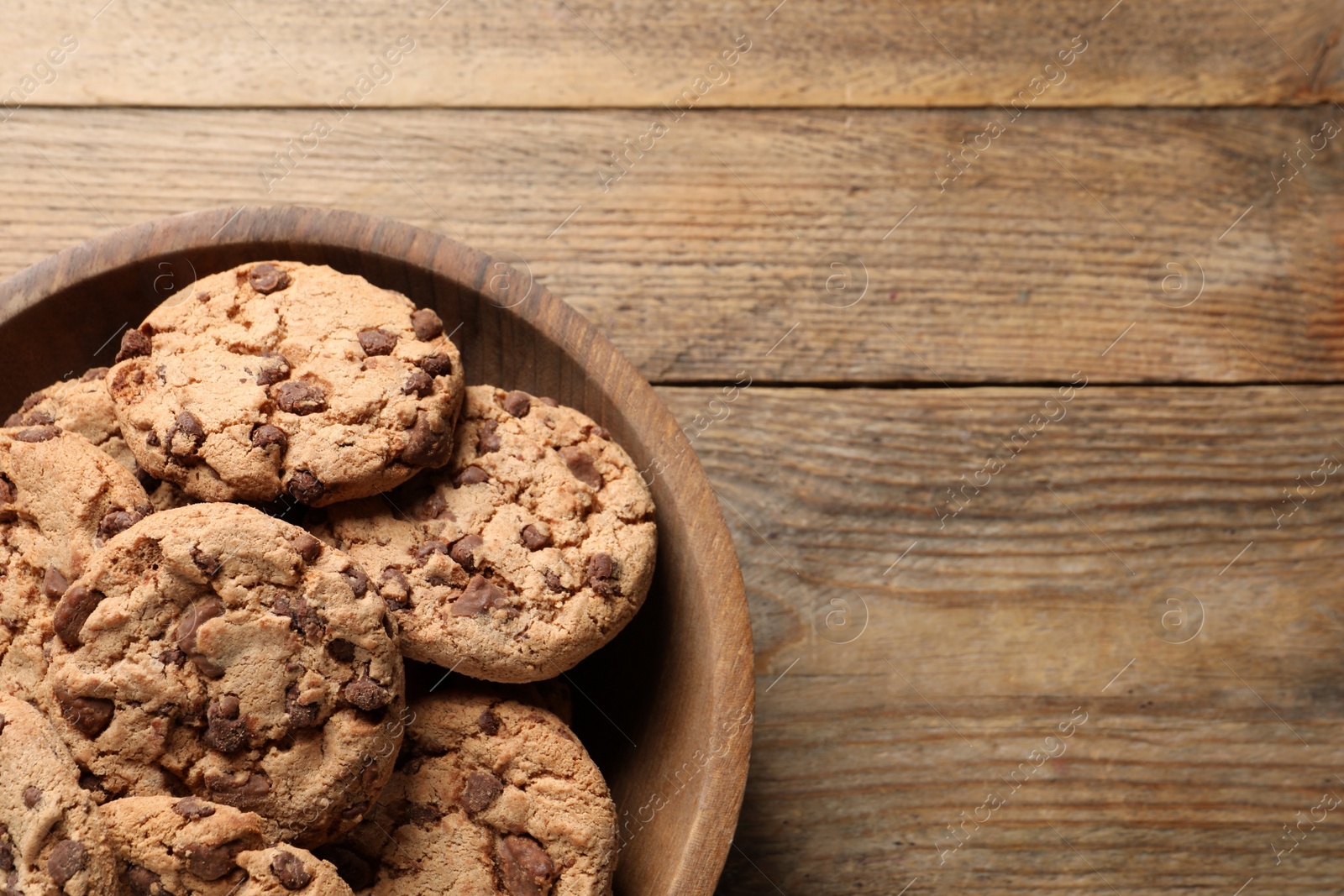 Photo of Delicious chocolate chip cookies on wooden table, top view. Space for text