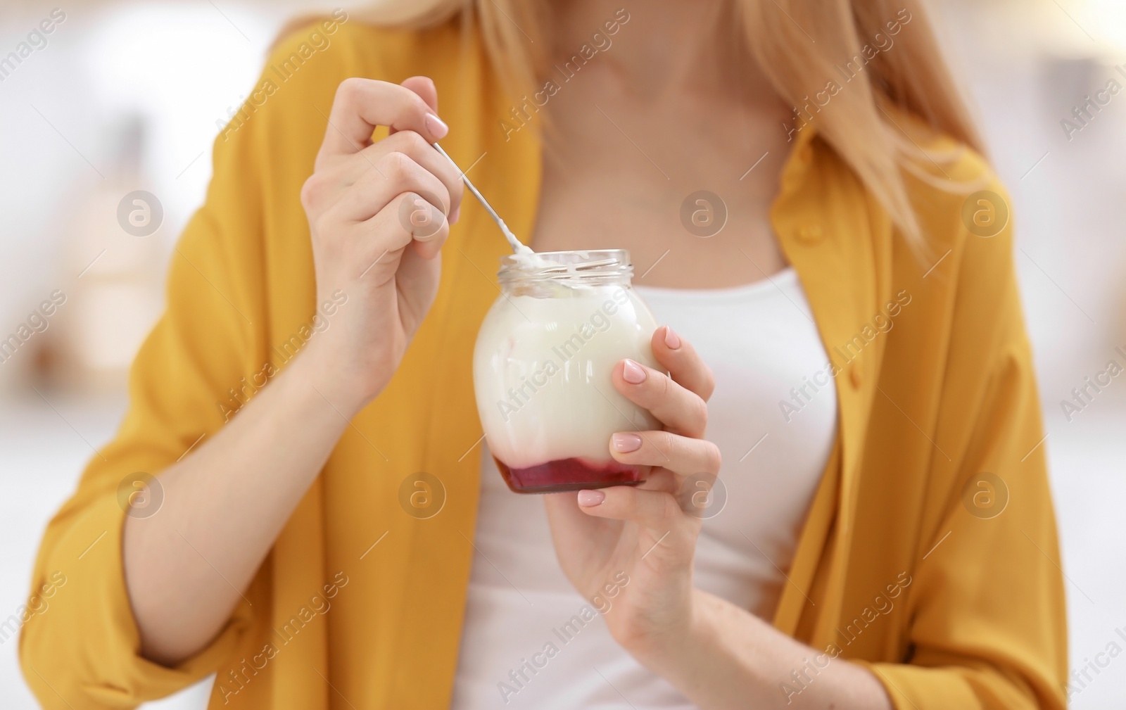 Photo of Young woman with yogurt on blurred background