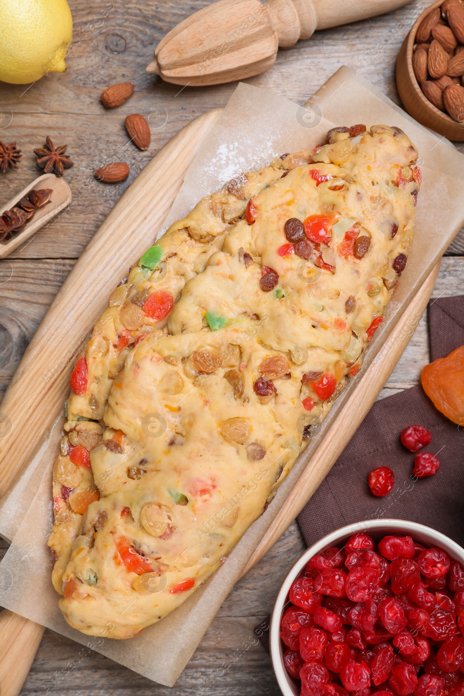 Photo of Unbaked Stollen with candied fruits and raisins on wooden table, flat lay