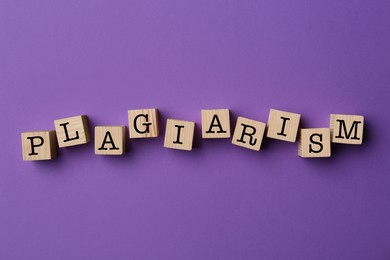 Word Plagiarism made of wooden cubes on violet background, top view