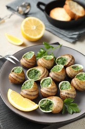 Photo of Delicious cooked snails served on light table