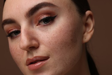 Photo of Portrait of beautiful woman with fake freckles on brown background, closeup