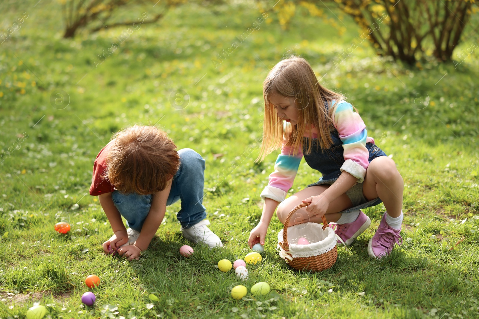 Photo of Easter celebration. Cute little children hunting eggs outdoors