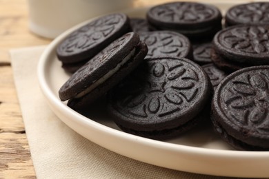 Photo of Plate with tasty sandwich cookies on wooden table, closeup