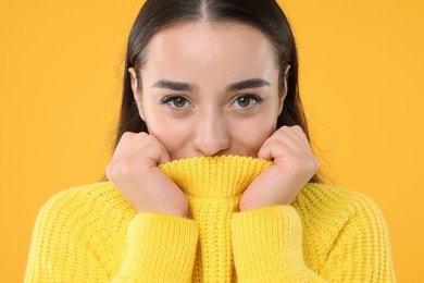 Photo of Beautiful young woman in stylish warm sweater on orange background