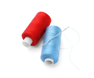 Different colorful sewing threads with needle on white background