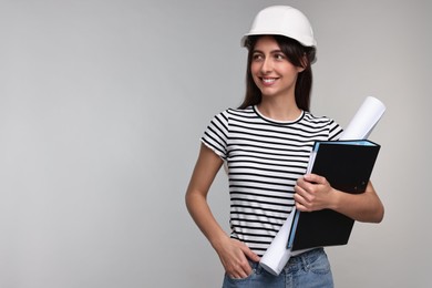 Architect in hard hat with draft and folder on light grey background, space for text
