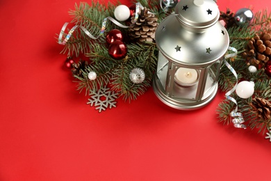 Photo of Christmas lantern with burning candle and festive decor on red background