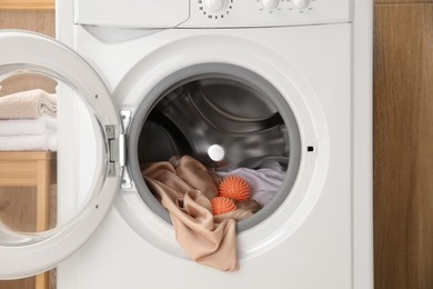 Photo of Dryer balls and clothes in washing machine, closeup