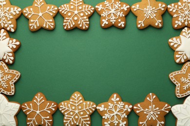 Photo of Frame made of tasty Christmas cookies with icing on green background, flat lay. Space for text