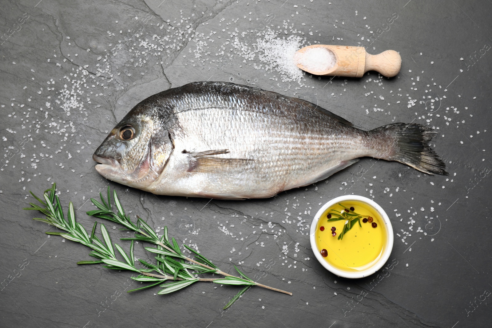 Photo of Flat lay composition with fresh raw dorado fish and ingredients on black table