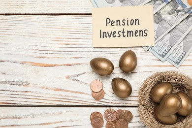 Photo of Golden eggs, money and card with phrase Pension Investments on white wooden table, flat lay. Space for text