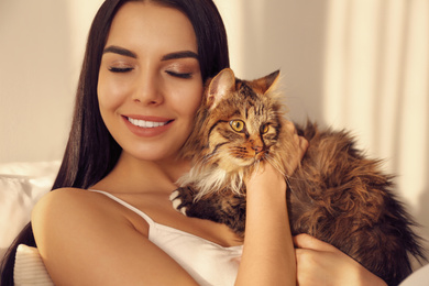 Photo of Beautiful young woman with her cute cat on bed. Fluffy pet