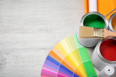 Photo of Cans of paint and decorator tools on wooden floor. Space for text