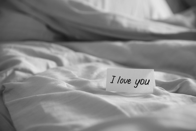 Note with text I Love You on bed. Romantic message