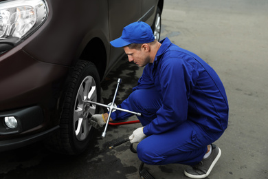 Worker checking tire pressure in car wheel at service station