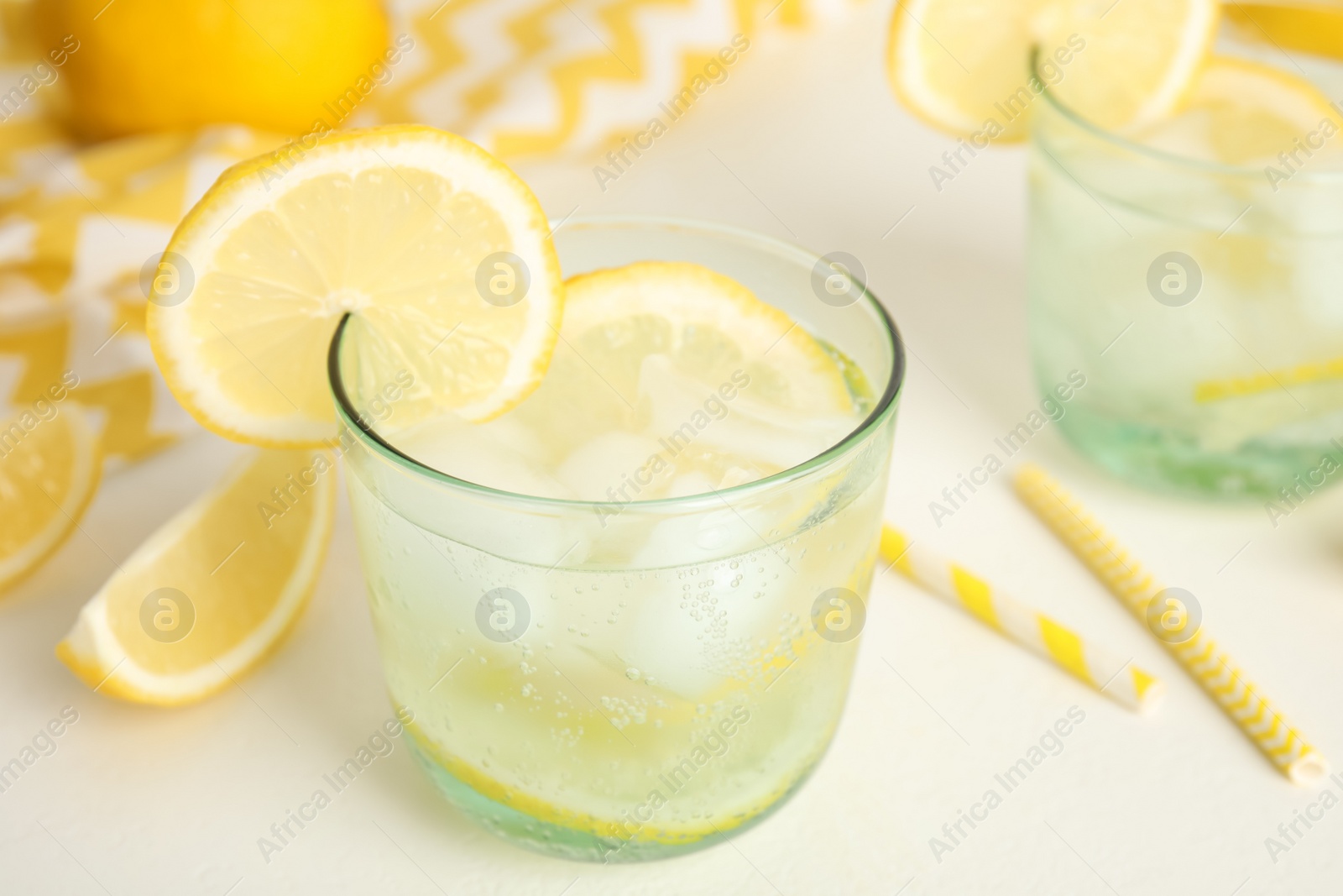 Photo of Soda water with lemon slices and ice cubes on white table