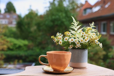 Cup of delicious chamomile tea and fresh flowers outdoors. Space for text