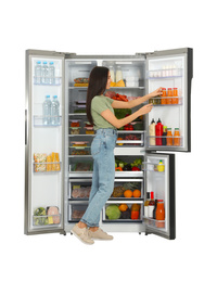 Young woman taking juice from refrigerator on white background
