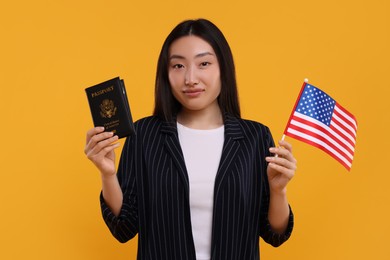 Immigration to United States of America. Woman with passport and flag on orange background