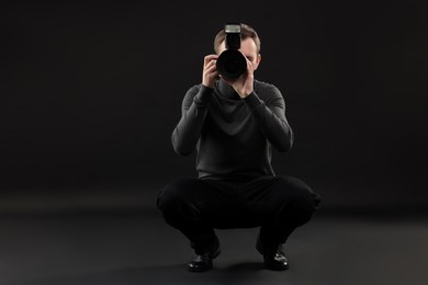 Professional photographer taking picture on black background