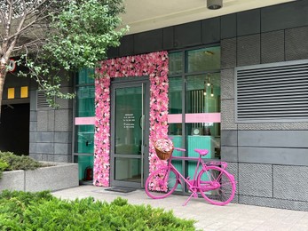 Photo of WARSAW, POLAND - JULY 13, 2022: Entrance of building decorated beautiful flowers and pink bicycle