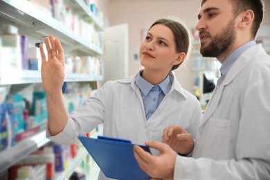 Photo of Professional pharmacists near shelves in modern drugstore