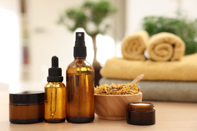 Photo of Bottles of essential oils, dry flowers and jars with cream on light wooden table, closeup. Spa therapy